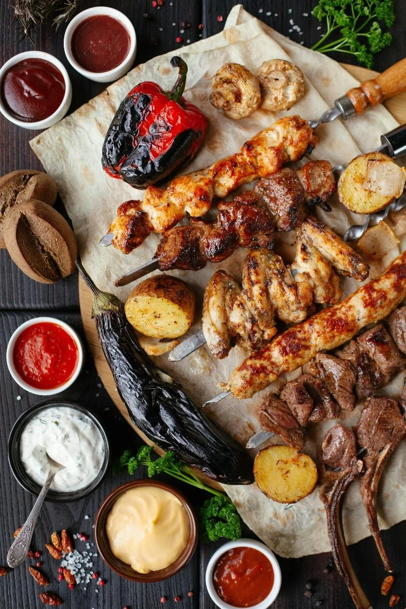 A platter with turkish kebebs, sauces, and other meat items