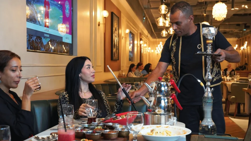 A waiter serving shisha to two women