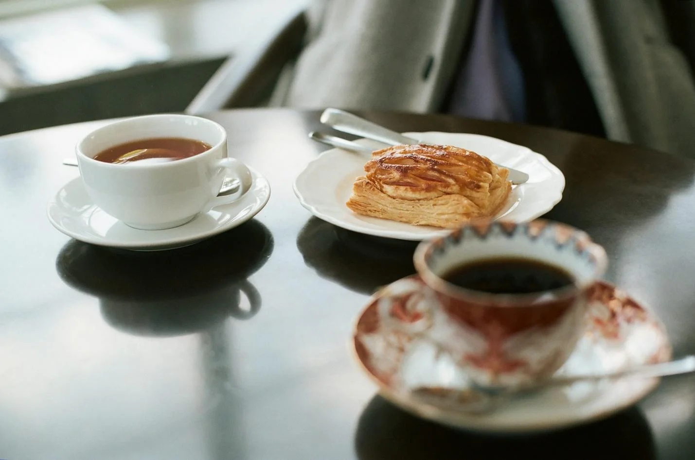 wo cups with tea and coffee, along with dessert on the table