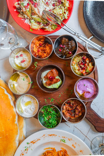 Colorful spread of traditional Turkish meze dishes served in small bowls, featuring a variety of sauces, salads, and appetizers on a wooden platter